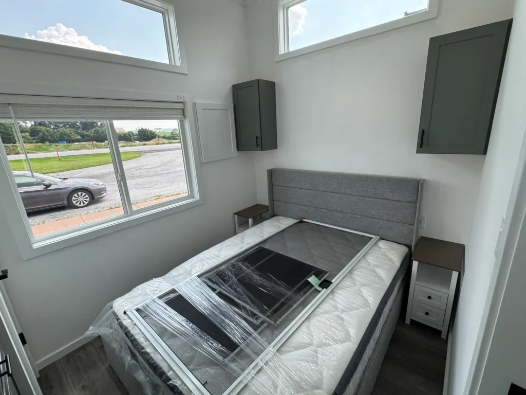 Master bedroom in a 2 bedroom park model cottage featuring built-in storage cabinets and large windows.