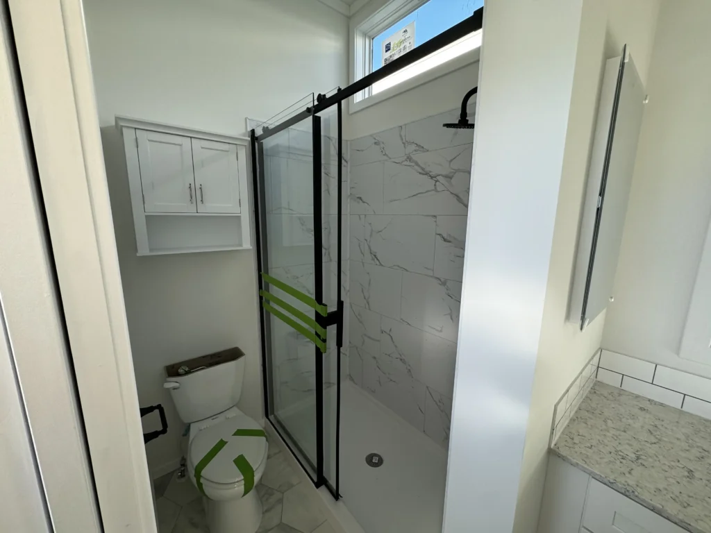 Park model bathroom interior featuring a residential toilet and a modern tile-surround walk-in shower.