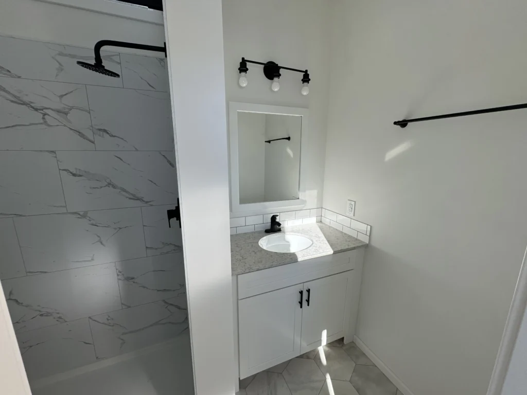 Glass-enclosed walk-in shower with large neutral wall tiles inside a Pillar Cabins custom cottage.