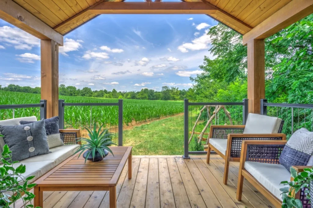 Luxury park model home with front porch deck and modern dark metal siding accents in a rural landscape.