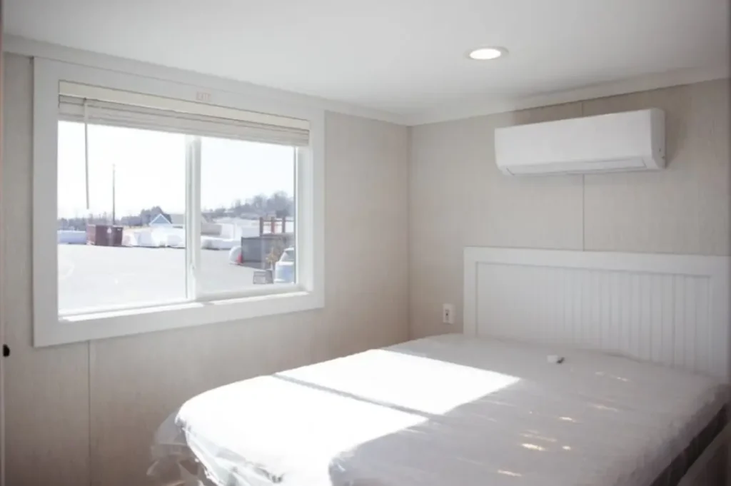 Park model bedroom featuring built-in storage cabinets, a white paneled door, and neutral walls.